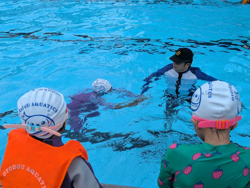 在新加坡泳池参加初级游泳课、戴着 Oyougu Aquatics 泳帽的孩子们
